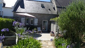Ein Steinhaus mit einem Gartenweg, der zu einer Terrasse mit Tisch und Stühlen führt.