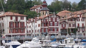 Marina com barcos atracados, rodeada por edifícios tradicionais com fachadas vermelhas e brancas.