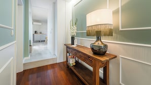 A hallway with a wooden console table, a lamp, and a vase with flowers. - Victoria Project - Apartment I - Private Parking (Porto)