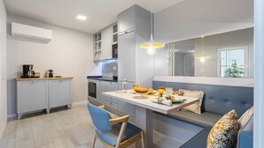 A modern kitchen with a built-in island, grey cabinetry, and a seating area with a bench and cushions. - Victoria Project - Apartment I - Private Parking (Porto)