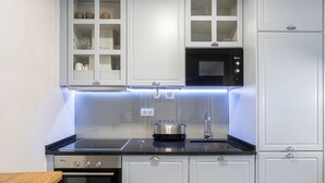 A modern kitchen with white cabinets, a black countertop, stainless steel appliances, and under-cabinet lighting. - Victoria Project - Apartment I - Private Parking (Porto)