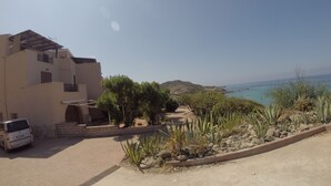 A coastal property with a paved driveway, a parked vehicle, and a view of the sea. - Exclusive penthouse overlooking the sea ....... with deserted beach under the house. (Alghero)