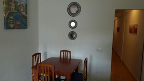 Ein Essbereich mit einem Holztisch und vier Stühlen, einem an der Wand befestigten Spiegel und einem Gemälde einer Kanalansicht.