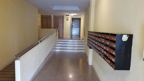Ein Flur mit Metallgeländer, einer Treppe und einem an der Wand befestigten Stauraum mit mehreren Fächern.