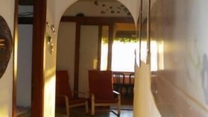 Un couloir avec une porte en bois, un espace détente avec des chaises et un sol carrelé.
