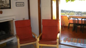 Une pièce avec deux chaises en bois, une cheminée et un balcon équipé d’une table et de chaises.