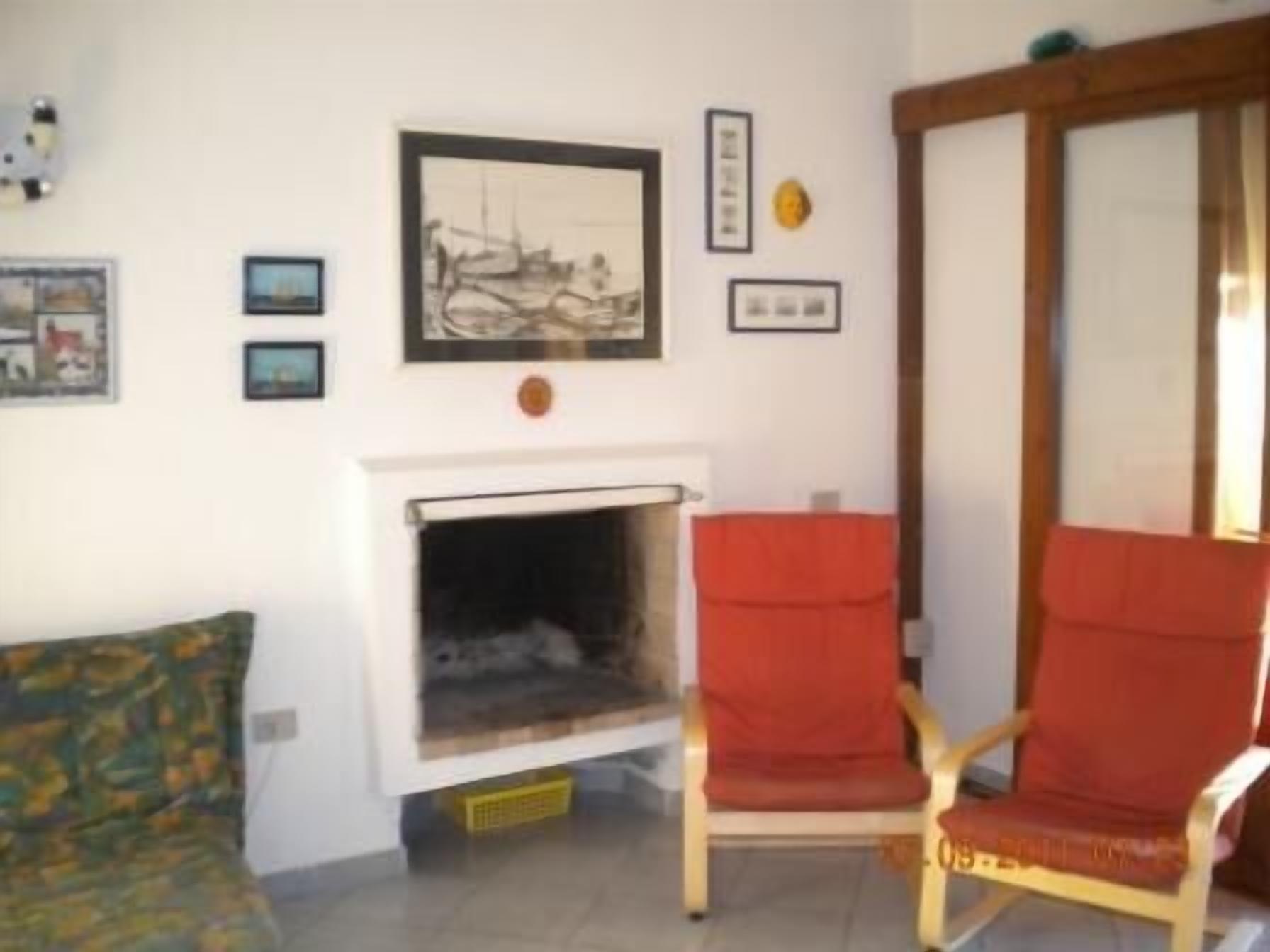 Ein Wohnzimmer mit Kamin, einem roten Sessel und einer Couch.