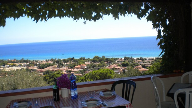 Une table dressée pour deux personnes, avec vue sur la mer et une ville en arrière-plan.