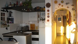 Une cuisine avec des armoires blanches, un plan de travail et une cuisinière. On y trouve une planche à découper en bois et un grille-pain posés sur le plan de travail.