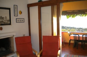 Quarto com duas cadeiras de madeira, lareira e varanda com mesa e cadeiras.