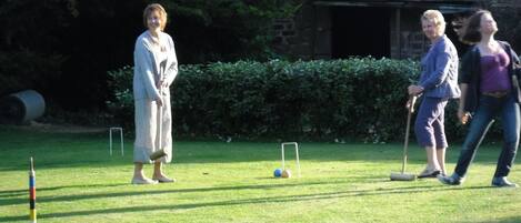 Un espace herbeux où est installé un jeu de croquet, avec une balle et des poteaux.