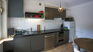 Eine moderne Küche mit Geschirrspüler, Backofen und Mikrowelle. Es gibt ein Spülbecken und eine Tafel mit Schrift.