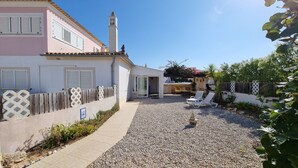 A house with a patio area, a small garden, and a white fence.