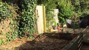 Een tuin met verhoogde borders, potplanten en tuinmeubilair.