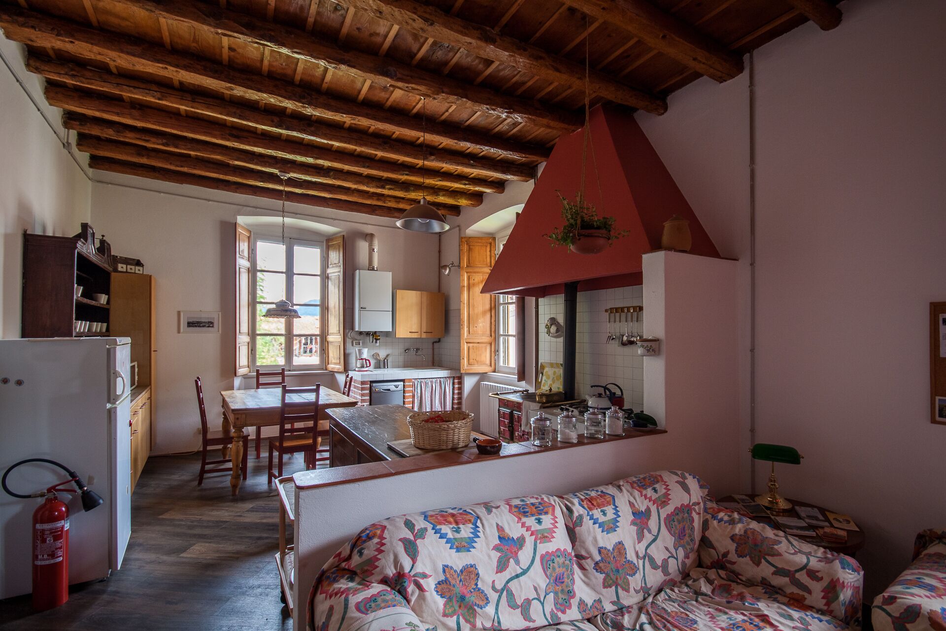 Un'accogliente cucina con travi in legno, un'area pranzo con tavolo e sedie, e un soggiorno con divano decorato.