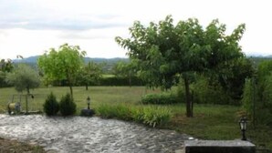 A stone pathway leading through a garden with trees and a lamp post. - Rochecolombe: Apartment/ flat - ROCHECOLOMBE (Rochecolombe)