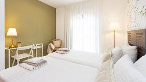 Une chambre d’hôtel avec deux lits, un bureau, une chaise et une lampe.