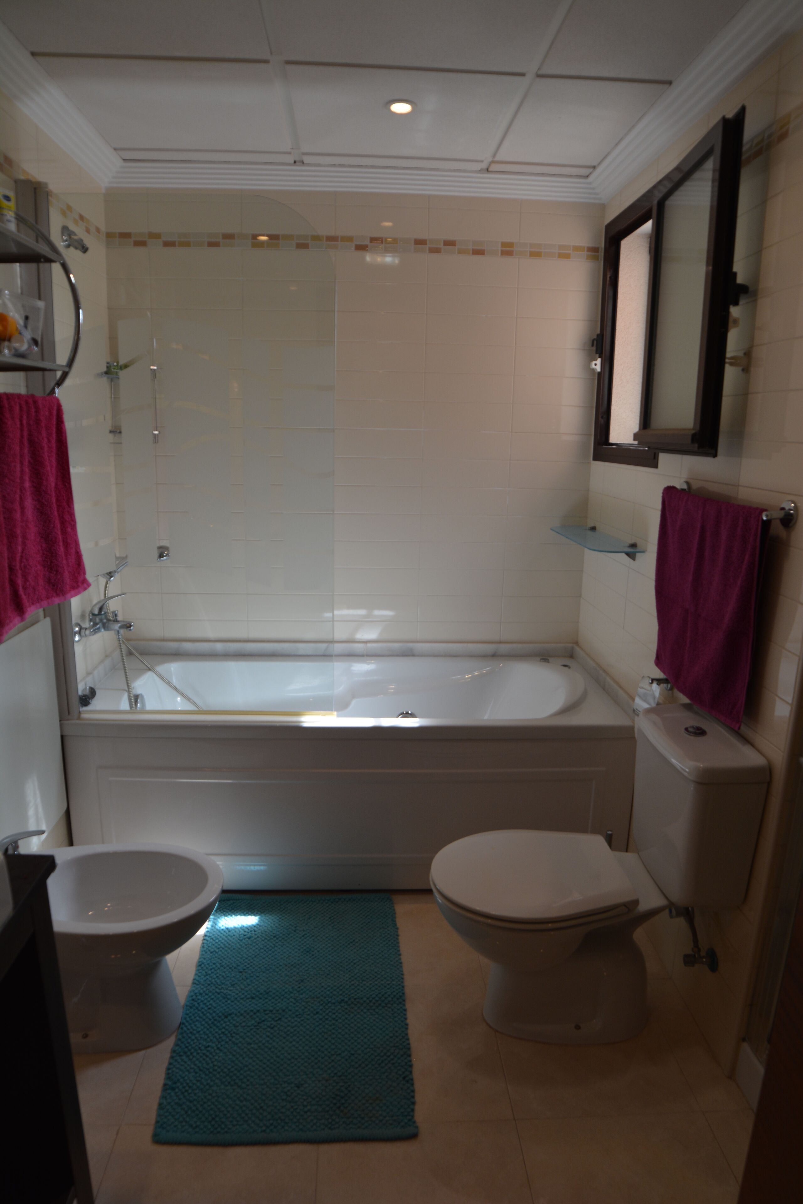 A bathroom with a bathtub, two toilets, a sink, and a shower.