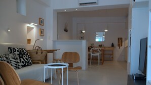 A modern living room with a sofa, chairs, a small table, and a TV.