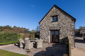 Guests can dine or relax on the patio, surrounded by a well-maintained lawn and hedge.