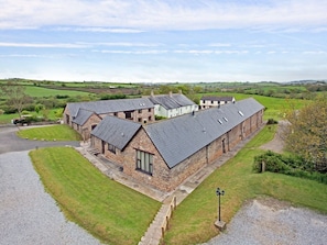 Traditional farmhouse with attached structures, surrounded by well-maintained lawns and a gravel driveway.