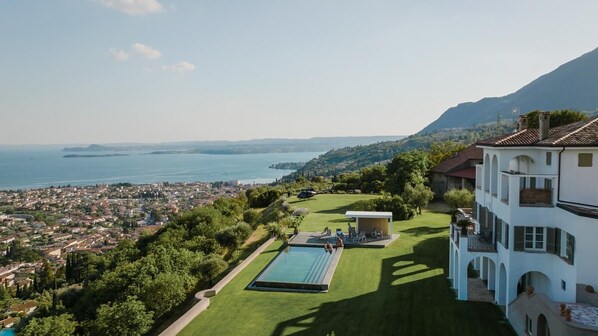 A large building with a swimming pool, a tennis court, and a view of the sea. - Storica Luxury Mansion (Toscolano-Maderno)