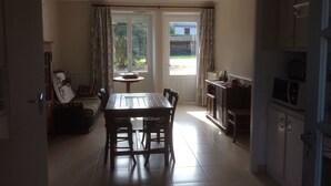 Un comedor con una mesa y sillas, un sofá y una zona de cocina con armarios y electrodomésticos.