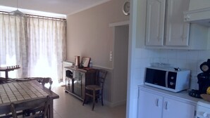 Una cocina con armarios blancos, un microondas y una mesa de comedor con sillas.