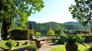 A garden patio with stone benches, potted plants, and a view of a mountainous landscape. - An 800 villa in the Tuscan countryside - a quiet place - pool - culture (Londa)