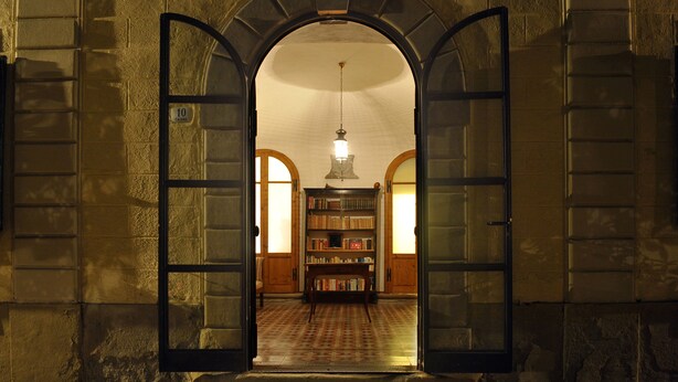 An arched doorway leading to a room with a patterned floor, a wooden bookshelf, and a hanging light fixture. - An 800 villa in the Tuscan countryside - a quiet place - pool - culture (Londa)