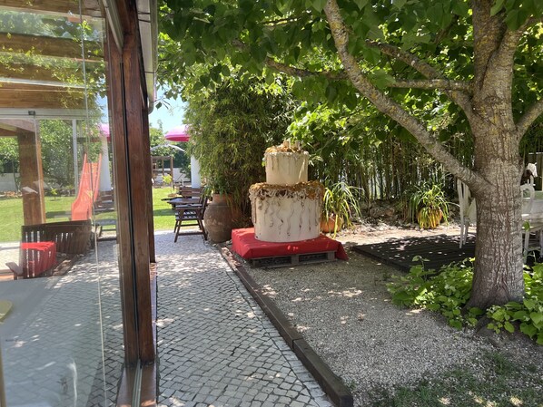 A garden area with a large tree, a pathway, and outdoor furniture.
