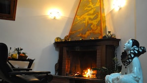 Une pièce avec une cheminée, un fauteuil noir et une statue décorative.