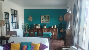 Ein Wohnzimmer mit einer Couch, Sesseln, einem Esstisch und einem großen Fenster.