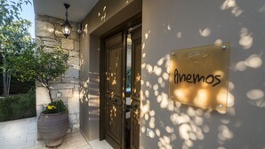 Entrada de um edifício com parede de pedra, um vaso de planta e uma placa com a inscrição 'Avenemos'.