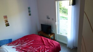 Een slaapkamer met een bed, een televisie op een houten tafel en een raam met gordijnen.