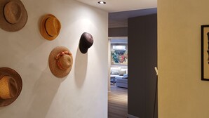 Ein Korridor mit einer Sammlung von Hüten an der Wand und einem gerahmten abstrakten Gemälde rechts.