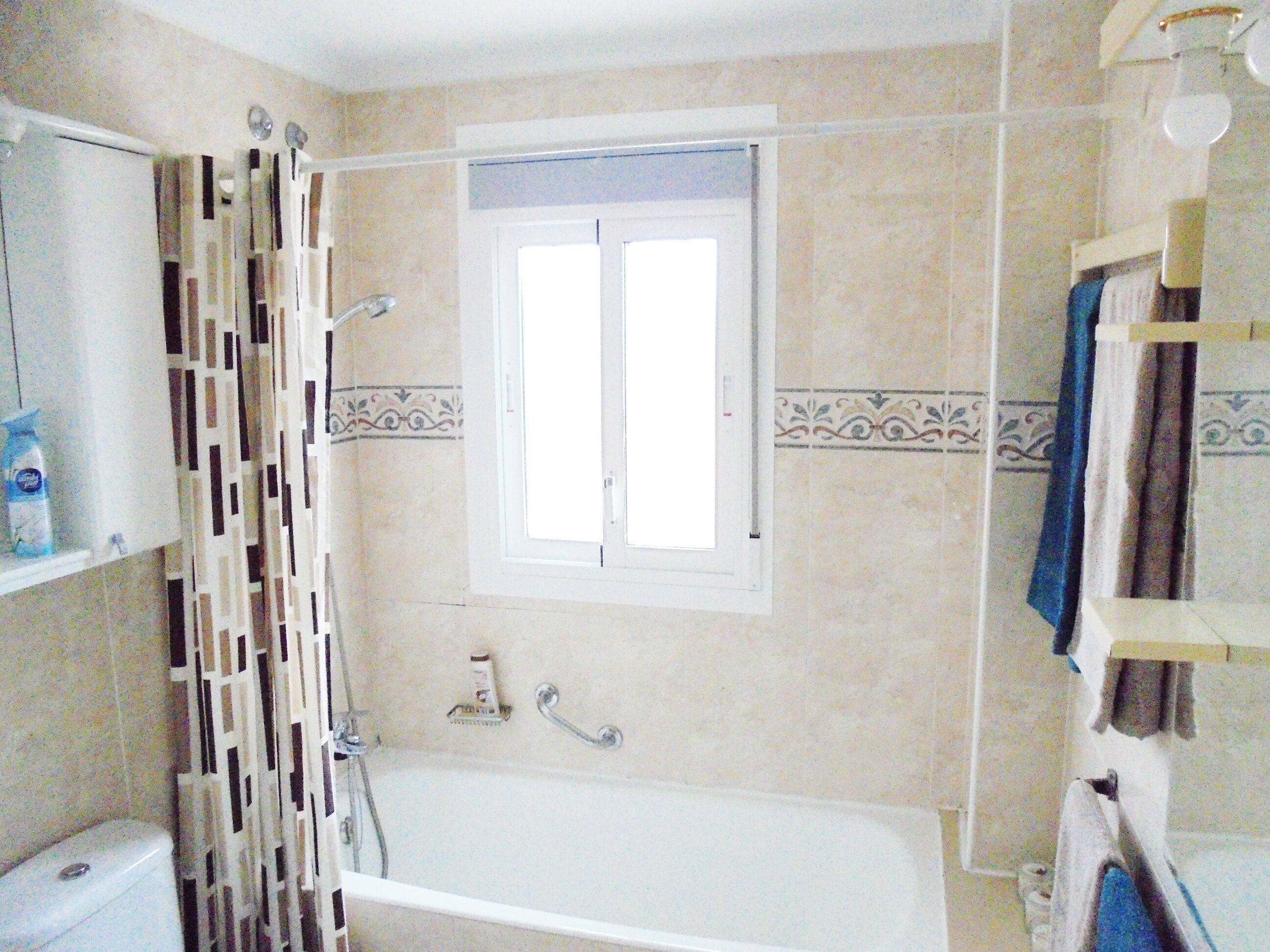 Un baño con bañera, inodoro, cortina de ducha y ventana.