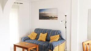 Een woonkamer met een bank, een salontafel, een vloerlamp en een schilderij aan de muur.