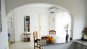 Een keuken met een eethoek, een kleine tafel met stoelen, een fruitschaal en een bloevas.
