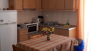 Uma cozinha com armários de madeira, micro-ondas, fogão, pia e mesa com toalha xadrez.