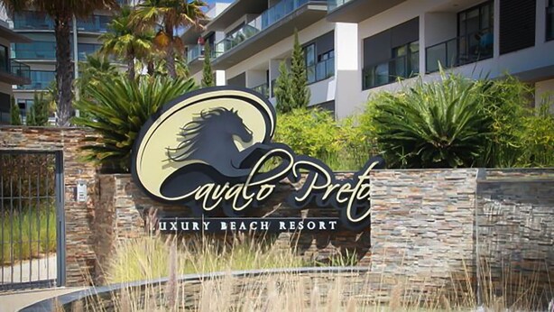 A sign for Cayo Retreat Luxury Beach Resort with a logo featuring a stylized horse and palm tree.