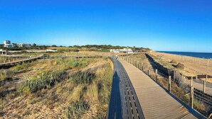 A wooden boardwalk along a beach with a clear sky.