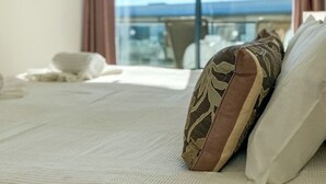 A hotel room with a bed, a view of the sea, and a balcony.