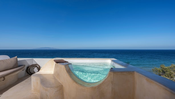 Una piscina privata con fondo in vetro, affacciata su un mare cristallino e una terraferma lontana.