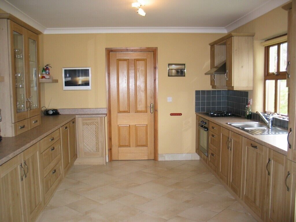 A kitchen with wooden cabinets, a tiled backsplash, a double sink, and a stove.
