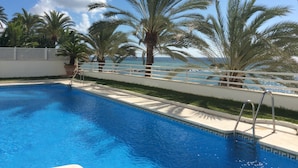 A swimming pool with a white deck, surrounded by palm trees and a view of the ocean. - Frontline Penthouse in quiet apartment block Marbella with stunning views  (Marbella)