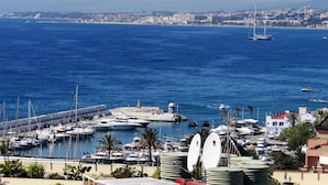 A marina with boats, a lighthouse, and a coastal cityscape in the background. - Frontline Penthouse in quiet apartment block Marbella with stunning views  (Marbella)