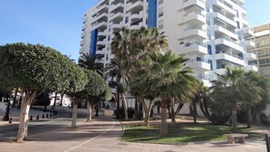 A multi-story hotel with balconies, surrounded by palm trees and a pedestrian pathway. - Frontline Penthouse in quiet apartment block Marbella with stunning views  (Marbella)