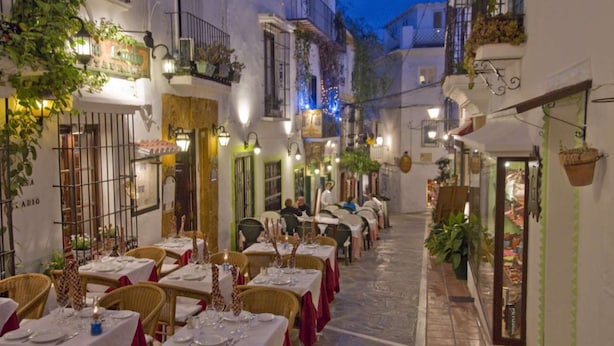 A narrow street lined with tables and chairs set up for dining, with buildings on either side. - Frontline Penthouse in quiet apartment block Marbella with stunning views  (Marbella)