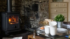 A cozy room with a wood-burning stove, a map, and a small table with cups and a plant. - Tan Y Graig, Rhyd-Ddu, Snowdonia (Rhyd-Ddu)